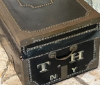 Unique antique black leather trunk with decorative brass handles, nail decoration and trim. Note on one end, the hand-painted initials (T H) and place of origin (NY). Measures 25" long x 12.5" wide x 10.5" high.